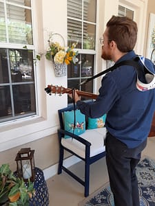 Tidewell music therapist Michael Russo provides a session through a window at an assisted living facility during pandemic